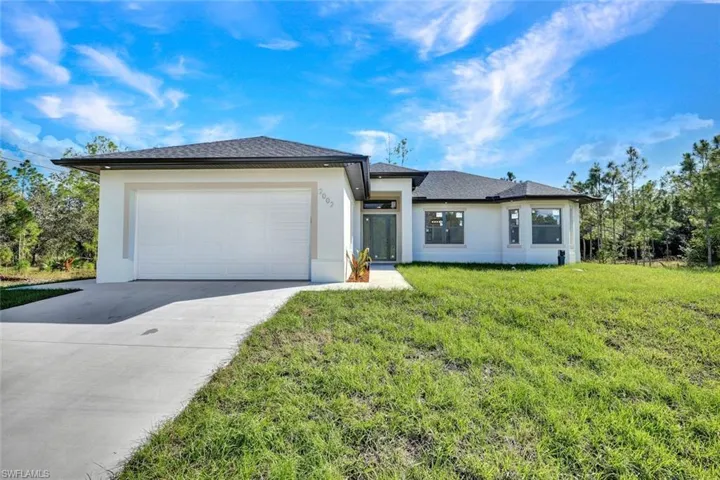 Prairie-style home with stucco siding, a front yard, driveway, and an attached garage