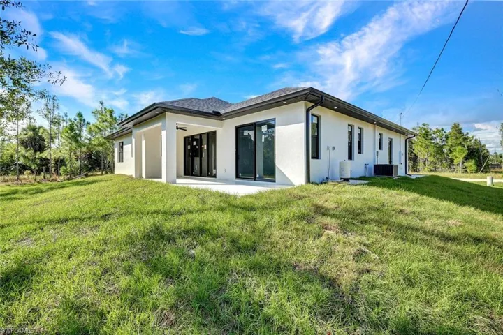Back of property featuring stucco siding, a lawn, and a patio