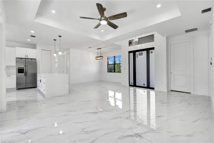 Unfurnished living room with a raised ceiling, light marble finish flooring, a ceiling fan, and recessed lighting