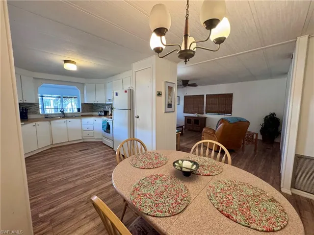 Dining area featuring dark wood-style flooring, visible vents, and a notable chandelier