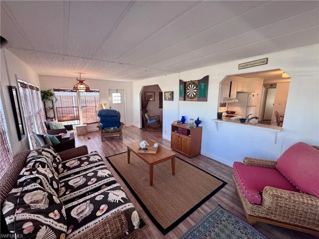 Living room with arched walkways, wood finished floors, and baseboards