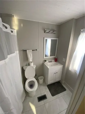 Bathroom with vanity, curtained shower, and light tile patterned flooring