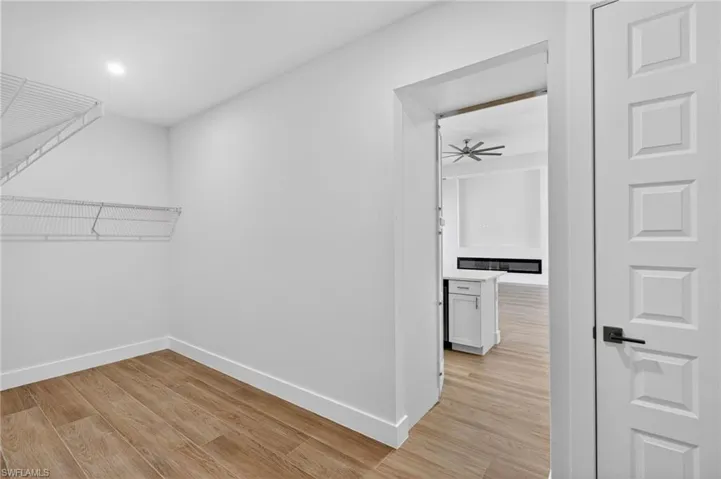 Spacious closet with light wood finished floors and ceiling fan