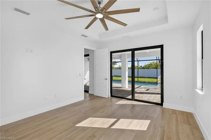 Spare room featuring light wood-style flooring, a tray ceiling, and a ceiling fan