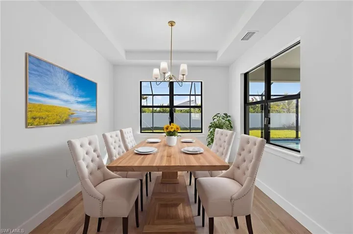 Dining area with a chandelier, light wood-style flooring, and a raised ceiling