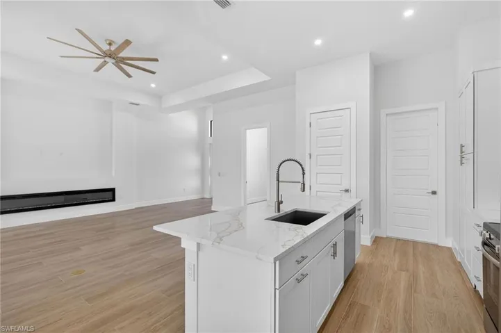 Kitchen featuring white cabinetry, light stone counters, recessed lighting, light wood finished floors, and open floor plan