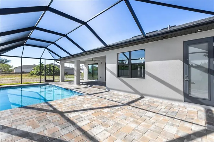 Outdoor pool featuring a sunroom, a patio area, and glass enclosure