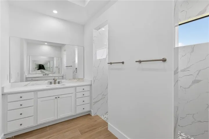 Full bath featuring vanity, a marble finish shower, and wood tiled floors