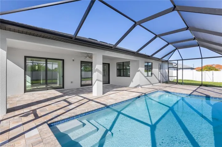 View of swimming pool with a sunroom, glass enclosure, and a patio