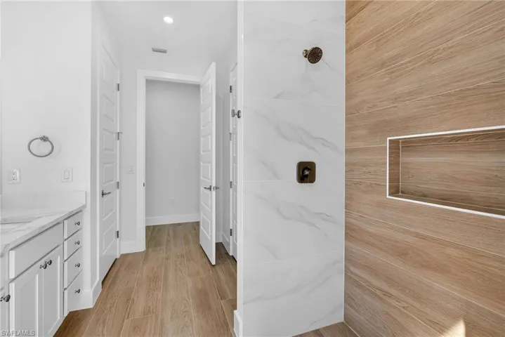 Full bathroom with vanity, light wood-style flooring, a tile shower, and recessed lighting