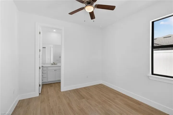Unfurnished bedroom with light wood-type flooring, a ceiling fan, and connected bathroom