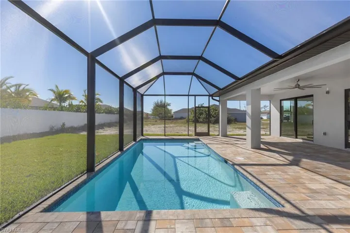 Swimming pool with a patio area, a lawn, a sunroom, and glass enclosure