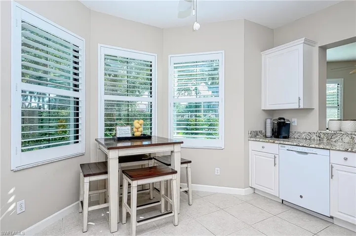 Kitchen featuring dishwasher, light stone counters, white cabinetry, light tile patterned floors, and ceiling fan