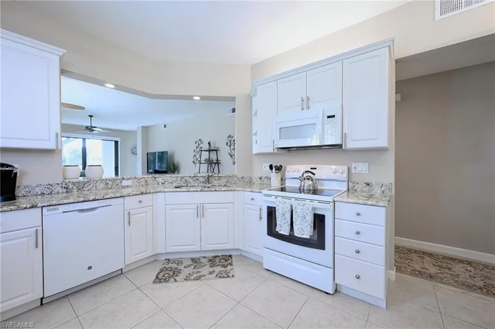 Kitchen featuring white cabinets, light tile patterned floors, and white appliances