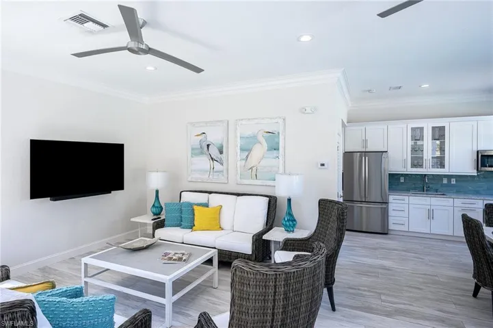 Living room with ceiling fan, ornamental molding, light wood-type flooring, and sink