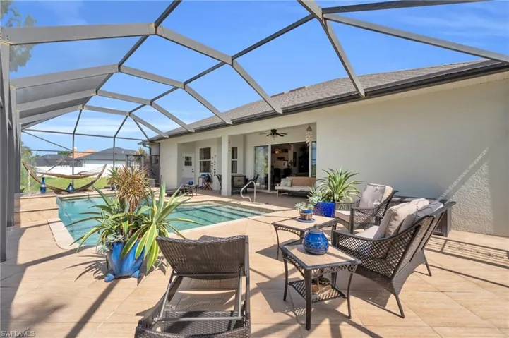 View of pool featuring an outdoor living space, a patio, ceiling fan, and glass enclosure
