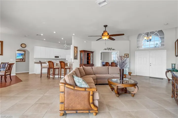 Living room featuring light tile patterned flooring and ceiling fan with notable chandelier