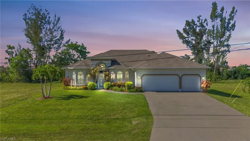 View of front of property with a garage and a yard