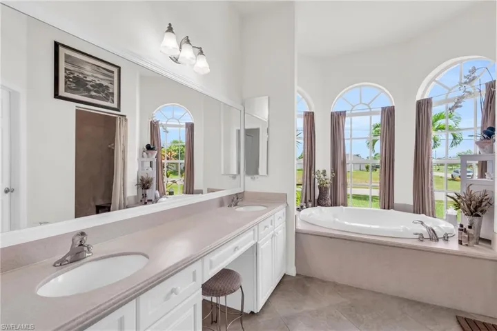 Bathroom with a tub to relax in, a wealth of natural light, and tile patterned flooring