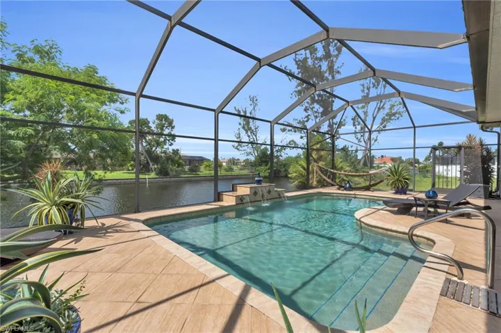 View of pool featuring a lanai, pool water feature, a water view, and a patio area