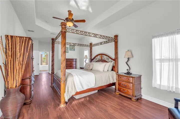 Bedroom featuring dark wood-type flooring, a raised ceiling, and ceiling fan