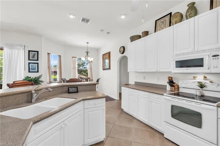 Kitchen with light tile patterned flooring, white cabinetry, white appliances, pendant lighting, and sink