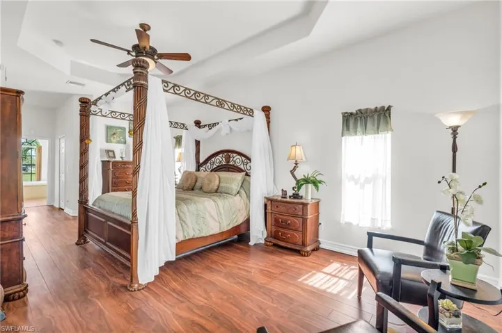 Bedroom featuring multiple windows, a raised ceiling, and hardwood / wood-style floors