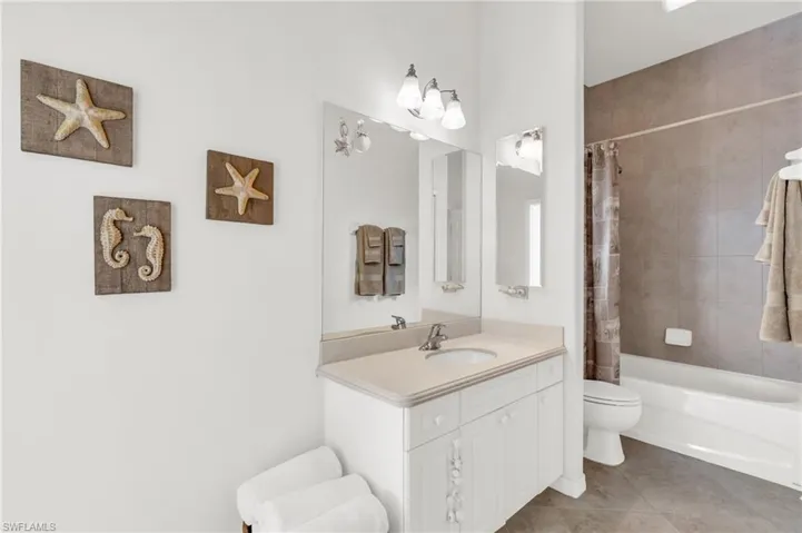 Full bathroom with tile patterned floors, vanity, shower / tub combo, and toilet
