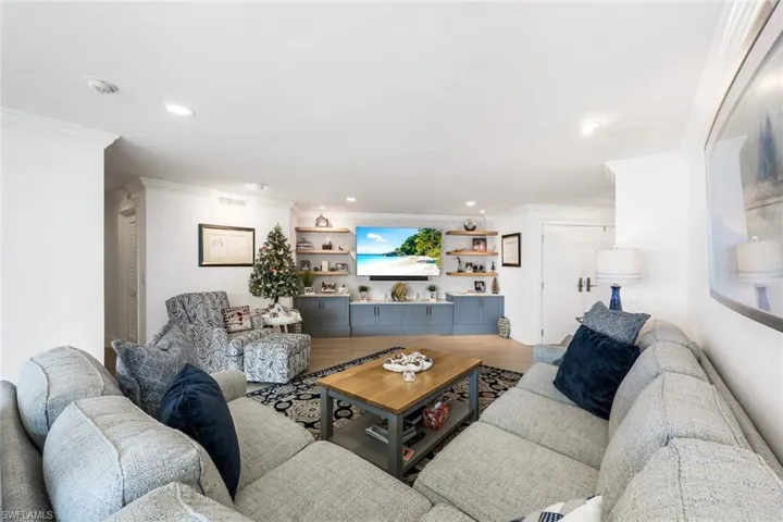 Living room featuring crown molding, built in features, and hardwood / wood-style flooring