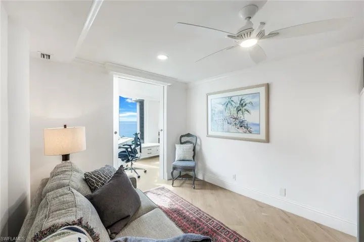 Living room featuring light wood-type flooring, ceiling fan, and ornamental molding