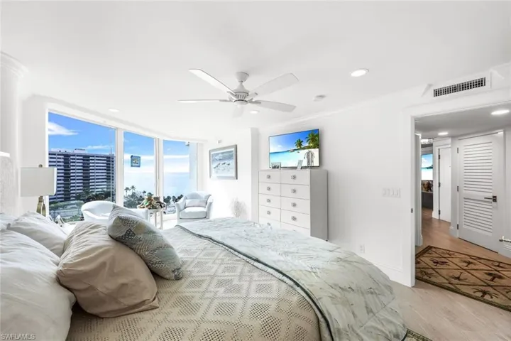 Bedroom featuring ceiling fan, expansive windows, light wood-type flooring, and ornamental molding