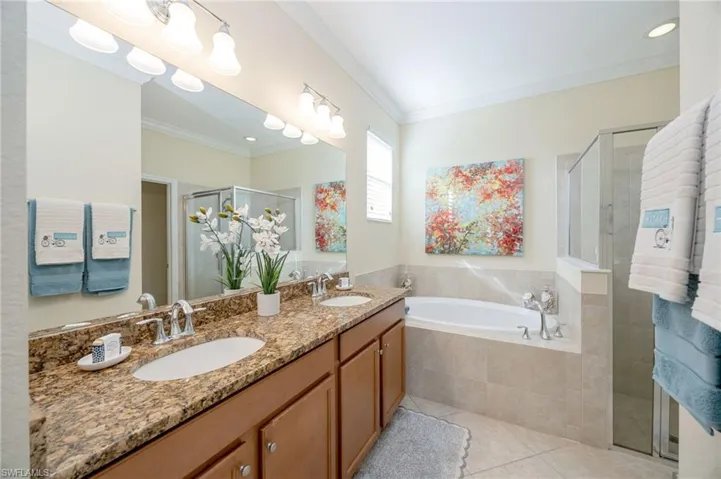 ensuite bathroom with soaking tub, shower, dual sinks and granite counters
