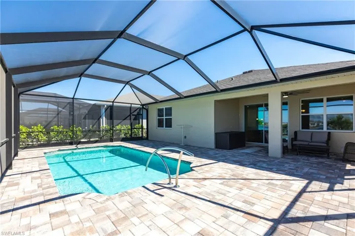 Pool with glass enclosure, an outdoor hangout area, a ceiling fan, and a patio
