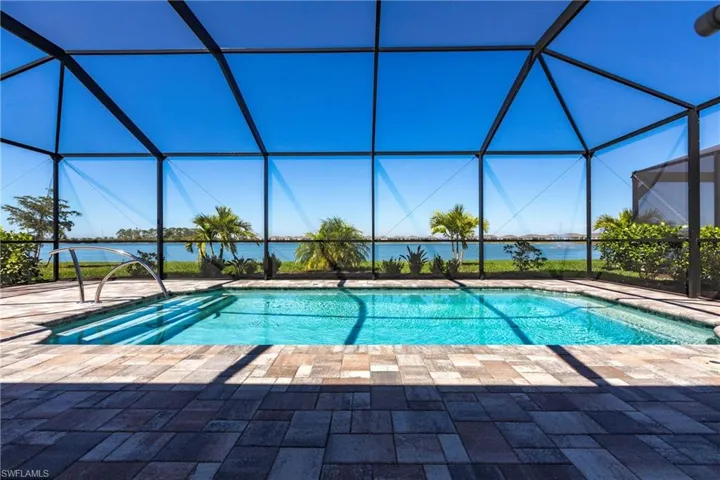 Outdoor pool featuring a water view, glass enclosure, and a patio