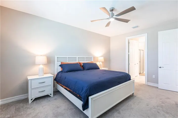 Bedroom featuring light carpet, baseboards, visible vents, a ceiling fan, and connected bathroom