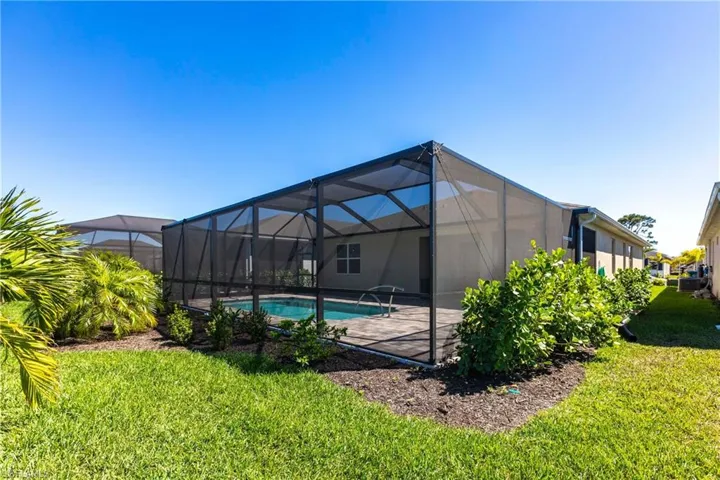 Rear view of property with a yard, a patio area, glass enclosure, and an outdoor pool