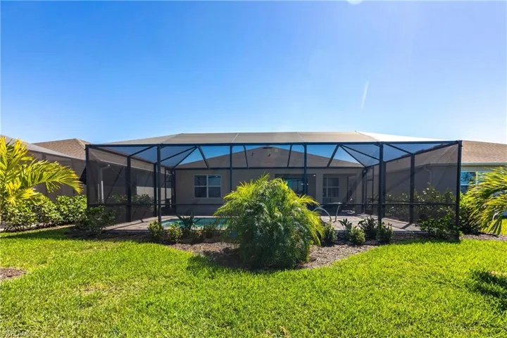 Back of property with a lanai, an outdoor pool, a lawn, and a patio