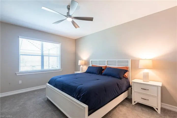 Bedroom with baseboards, a ceiling fan, and light colored carpet