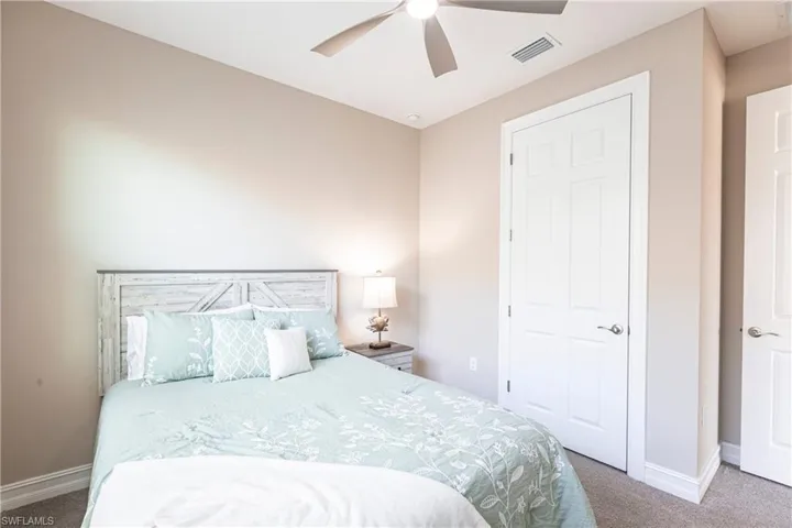 Carpeted bedroom with baseboards, visible vents, and ceiling fan