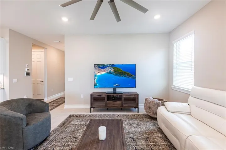 Living room with baseboards, a ceiling fan, and recessed lighting