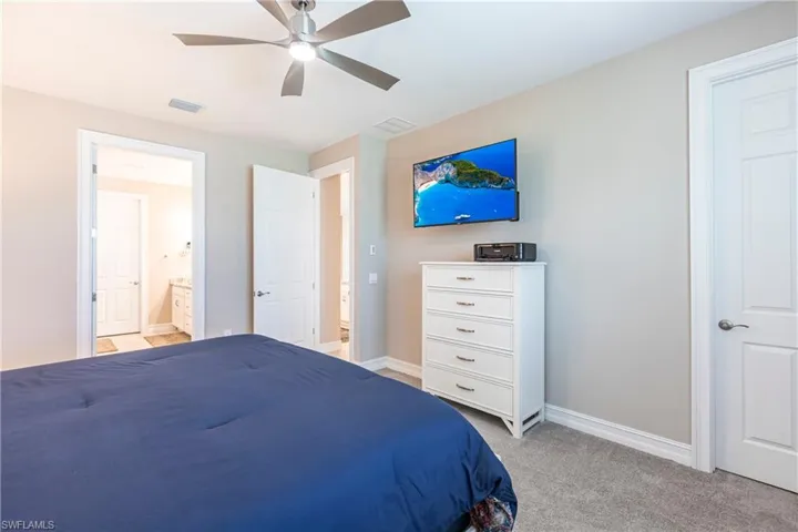Bedroom featuring baseboards, visible vents, connected bathroom, and light colored carpet