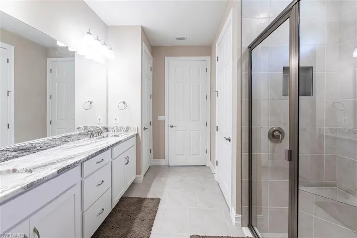 Bathroom with a sink, double vanity, and a shower stall