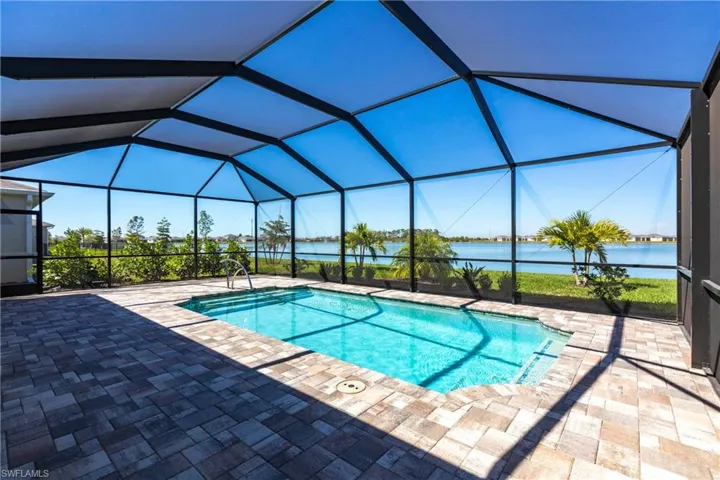 Pool with a water view, glass enclosure, and a patio