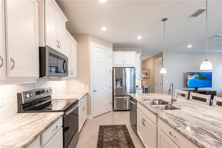 Kitchen with visible vents, decorative backsplash, stainless steel appliances, white cabinetry, and a sink