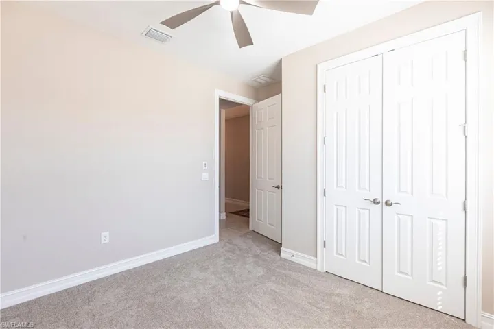 Unfurnished bedroom featuring light carpet, baseboards, visible vents, ceiling fan, and a closet