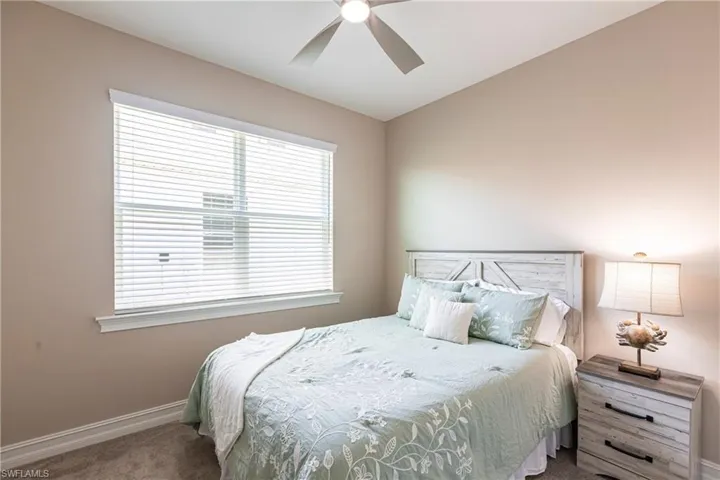 Carpeted bedroom with ceiling fan and baseboards