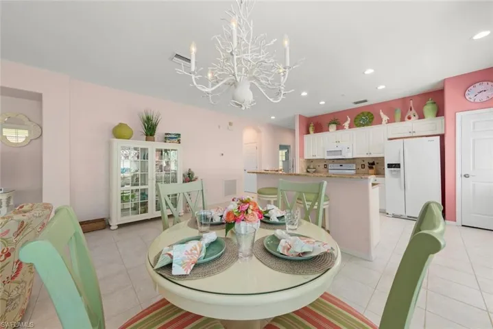 Open-concept kitchen featuring a breakfast bar with stone-finish countertops, white cabinetry, recessed lighting, and a decorative chandelier