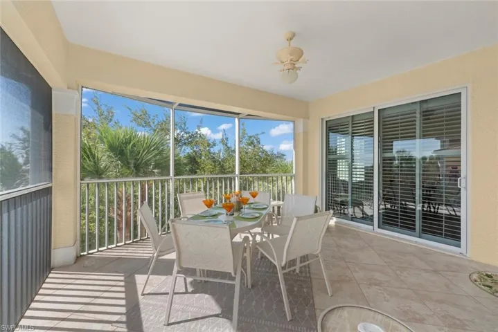 Screened-in lanai featuring large-format tile flooring, a ceiling-mounted light fixture, and floor-to-ceiling glass sliding doors