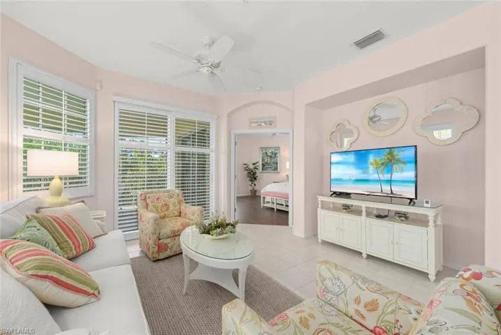 Living area featuring tile flooring, a recessed media alcove, plantation shutters, and a multi-blade ceiling fan