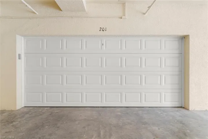 White panel garage door featuring a smooth finish, textured wall surfacing, and concrete flooring